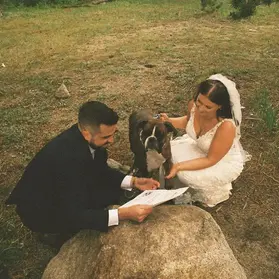 Two brides with their dog during a mountain wedding ceremony