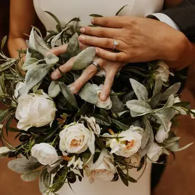 Close-up of wedding rings resting on a vibrant flower bouquet
